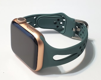 May include: A rose gold Apple Watch with a dark green silicone sport band. The band has a unique design with cutouts and holes.