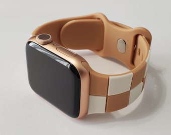 May include: A rose gold Apple Watch with a brown and white chequered silicone band.