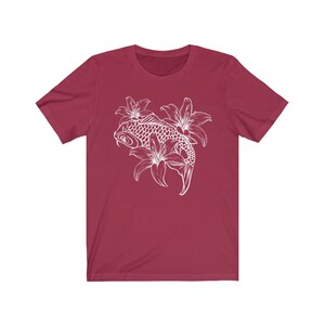 May include: A maroon t-shirt with a white outline of a koi fish swimming through lilies.