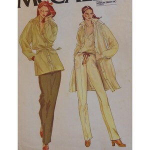 May include: A vintage sewing pattern featuring two women wearing different outfits. The woman on the left is wearing a long-sleeved shirt with a belt and brown trousers. The woman on the right is wearing a long-sleeved shirt with a white top and white trousers. The pattern is from the Norton Simon Inc. company.