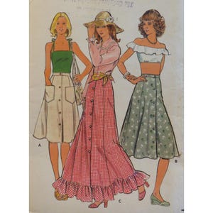 以下が含まれることがあります： ヴィンテージの服を着た3人の女性のイラスト。1人はグリーントップとボタン付きスカート、もう1人はピンクのブラウスとチェック柄スカート、もう1人は白いクロップトップと花柄スカートを着ています。画像はヴィンテージの縫製パターンです。