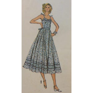 Puede incluir: Ilustración de un vestido vintage con estampado floral azul y blanco. El vestido tiene un corpiño ajustado, una falda amplia y tirantes finos atados a los hombros. Un borde decorativo adorna el dobladillo. El número "1" está en la parte inferior.