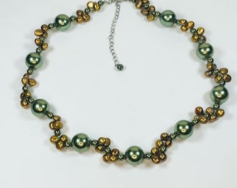 May include: A green and gold beaded necklace with a silver clasp. The necklace is made of round green beads and smaller gold beads.
