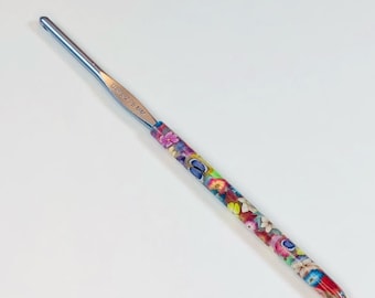 May include: A silver crochet hook with a floral and butterfly design. The hook is 3.5 mm.