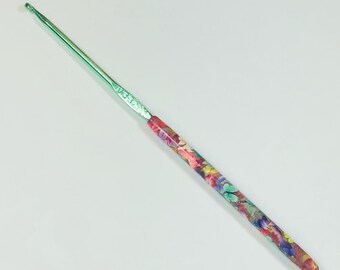May include: A green crochet hook with a colorful floral and butterfly design on the handle.