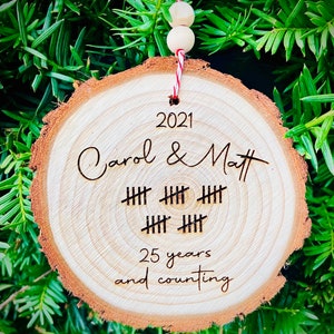 May include: A wooden ornament with the text "2021 Carol & Matt" and "25 years and counting" with tally marks representing 25 years.