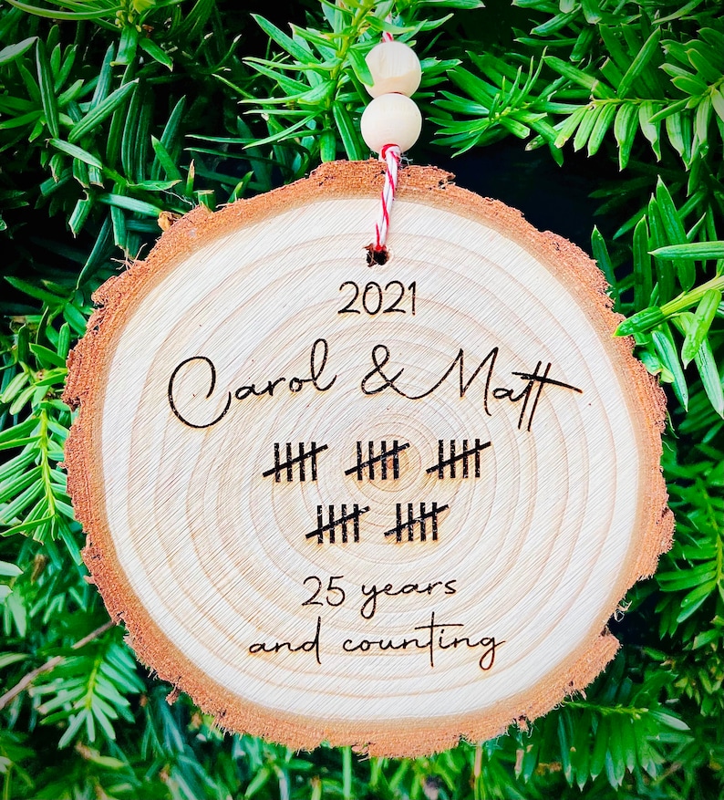 May include: A wooden ornament with the text "2021 Carol & Matt" and "25 years and counting" with tally marks representing 25 years.