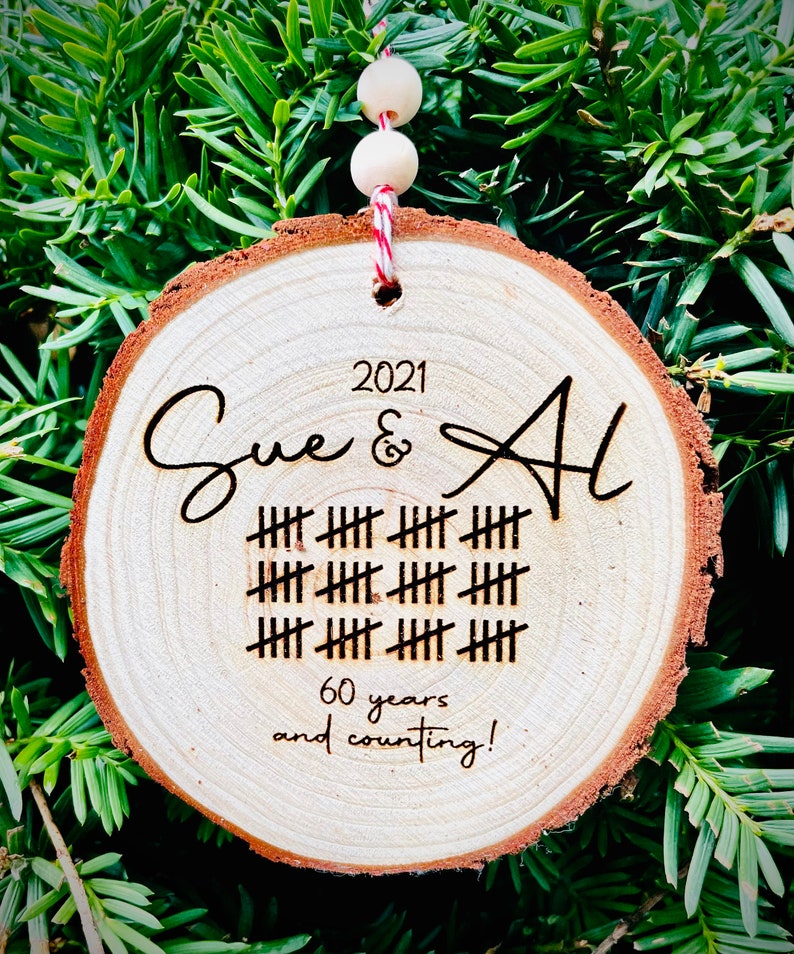 May include: A wooden round ornament with the names Sue & Al, the year 2021, and 60 years and counting! engraved on it.