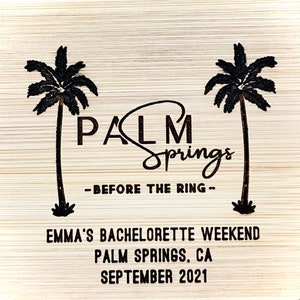 May include: A wooden sign with the text "Palm Springs - Before the Ring - Emma's Bachelorette Weekend Palm Springs, CA September 2021" and two palm trees.