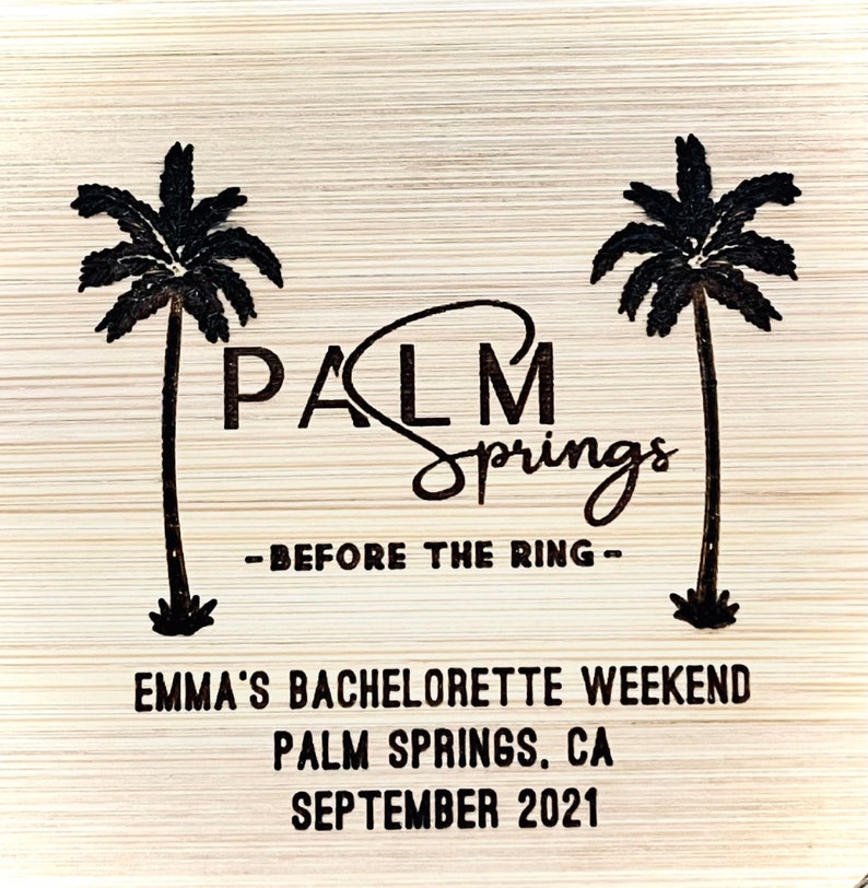 May include: A wooden sign with the text "Palm Springs - Before the Ring - Emma's Bachelorette Weekend Palm Springs, CA September 2021" and two palm trees.