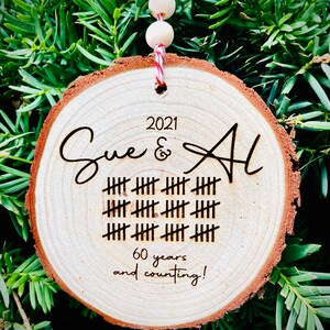May include: A wooden round ornament with the names Sue & Al, the year 2021, and 60 years and counting! engraved on it.