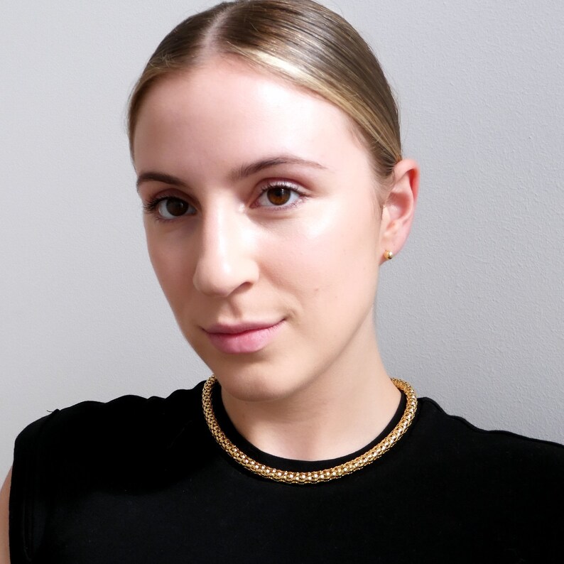 Op de afbeelding: Een vrouw draagt een zwart topje met een gouden ketting.