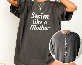 May include: A dark gray oversized t-shirt with the text "Swim like a Mother" printed on the front. The back of the shirt has the text "malcolm - taylor" printed vertically down the center.