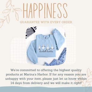 K&ouml;nnte beinhalten: Hellblaues Sweatshirt mit einem G&auml;nsemotiv und dem Text "barbell baddie". Das Wort "HAPPINESS" ist oben im Bild zu sehen, sowie der Text "GUARANTEE WITH EVERY ORDER".
