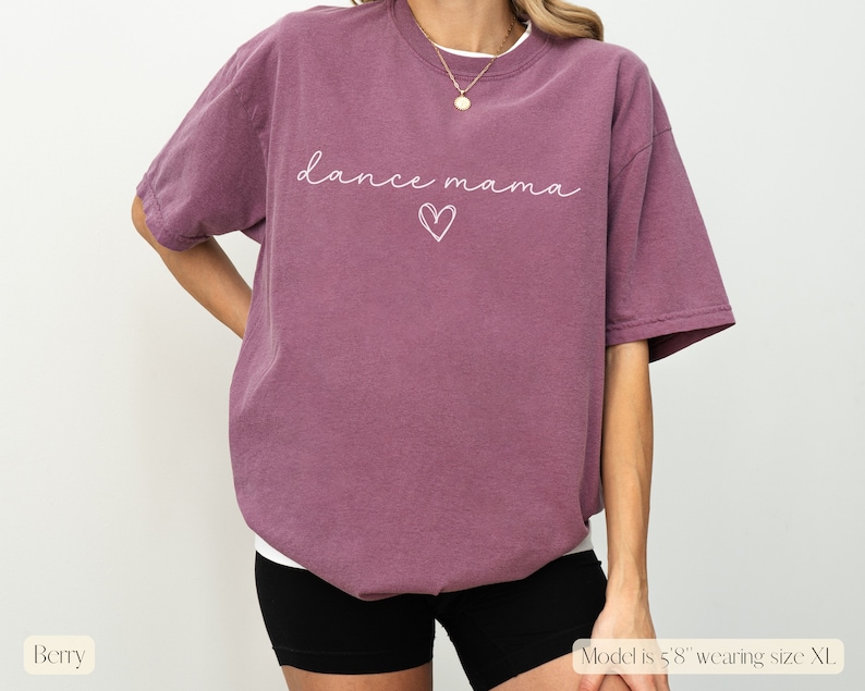 K&ouml;nnte beinhalten: Ein mauvefarbenes T-Shirt mit dem Text "dance mama" und einer Herzgrafik in Wei&szlig;.