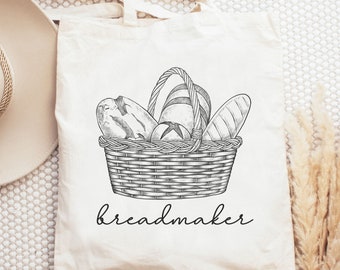 May include: A white tote bag with a black and white illustration of a basket full of bread. The text "breadmaker" is printed below the basket.