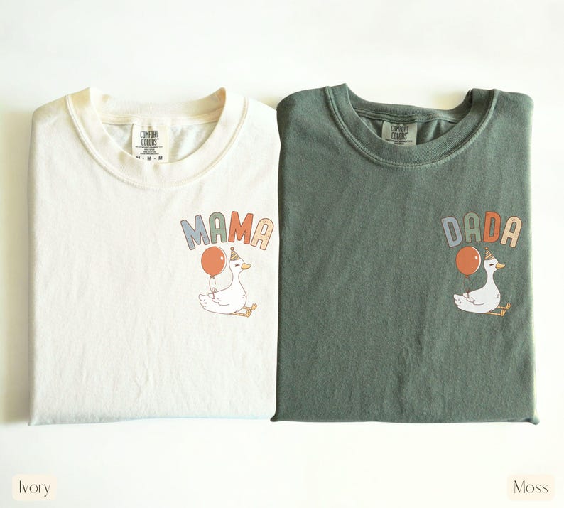 Puede incluir: Dos camisetas Comfort Colors, marfil y verde musgo, con gr&aacute;ficos a juego. Cada camiseta presenta un ganso de dibujos animados sosteniendo un globo, con las palabras "MAMA" y "DADA" encima del ganso. La camiseta marfil est&aacute; etiquetada como "Ivory" y la camiseta verde como "Moss".