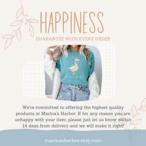 May include: A teal blue t-shirt with a white graphic of a goose with the text "Mama Goose" and "Est. 2020". The t-shirt is being worn by a person with a white cardigan and blue jeans. The text "Happiness Guarantee with Every Order" is at the top of the image.