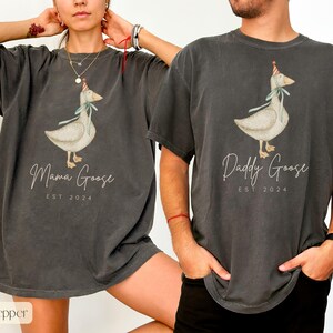 May include: Two gray t-shirts with a goose wearing a party hat and the text "Mama Goose Est 2024" and "Daddy Goose Est 2024".