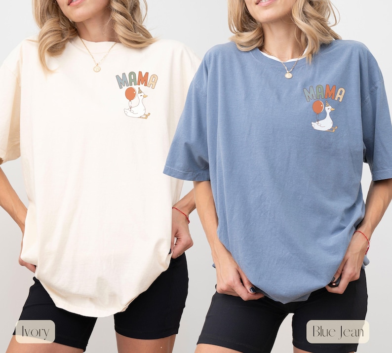 Puede incluir: Camisetas color marfil y azul vaquero con la palabra "MAMA" y un dibujo de un ganso con un globo. La camiseta marfil tiene pantalones cortos negros, y la camiseta azul vaquero tiene pantalones cortos negros. Las camisetas son de manga corta y de corte holgado.