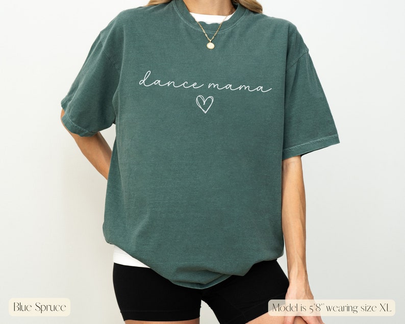 K&ouml;nnte beinhalten: Ein &uuml;berdimensioniertes T-Shirt in Tealblau mit dem Text "dance mama" in wei&szlig;er Schrift mit einem darunter gezeichneten Herzen.