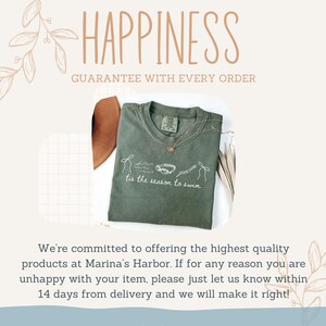 May include: Olive green t-shirt with the text "tis the season to swim" and a graphic of swimming goggles and a swimmer. The word "HAPPINESS" is written in a decorative font above the shirt.