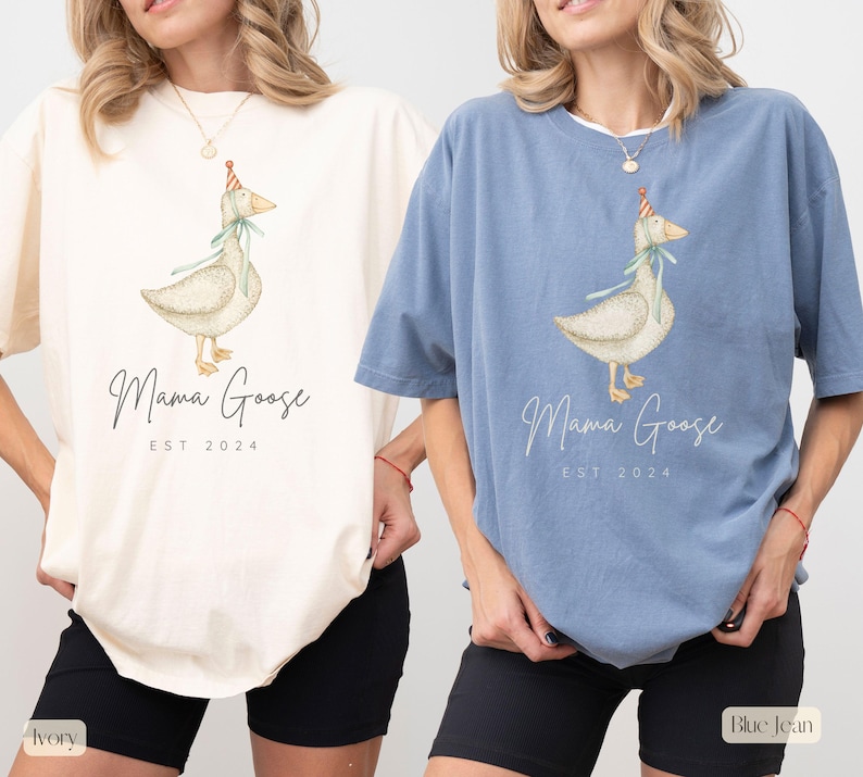 May include: Two women wearing oversized t-shirts with a goose wearing a party hat and the text "Mama Goose Est. 2024". The woman on the left is wearing an ivory t-shirt and the woman on the right is wearing a blue jean t-shirt.