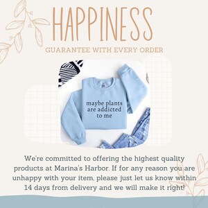 May include: A light blue sweatshirt with the text "maybe plants are addicted to me" in black. The word "HAPPINESS" is at the top of the image. The sweatshirt is paired with denim jeans and a striped accessory.