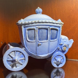 May include: A blue ceramic carriage figurine with gold accents. The carriage has a domed top and wheels with intricate details.