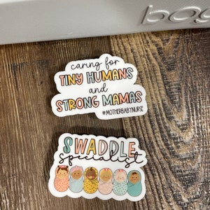 May include: Two stickers with a baby theme. The first sticker is white with a pink, blue, and yellow cloud shape. The text on the sticker reads "caring for TINY HUMANS and STRONG MAMAS #MOTHERBABY NURSE". The second sticker is white with a pink, blue, and yellow swirly design. The text on the sticker reads "SWADDLE SPECIALIST" and features a row of six cartoon babies in swaddles.