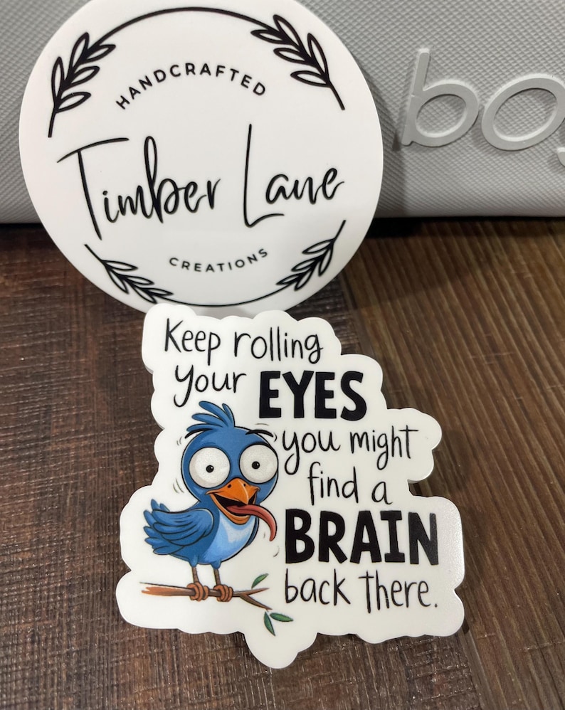 May include: A white sticker with a blue bird cartoon with a tongue sticking out. The text on the sticker reads "Keep rolling your EYES you might find a BRAIN back there."
