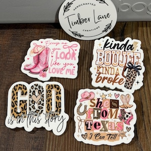 May include: A collection of handcrafted stickers with a country theme. Designs include pink cowboy boots, the phrase "Excuse me you look like you love me," and the text "God is in this story." Other stickers say "kinda boujee kinda broke" and "She's from Texas I Can Tell."