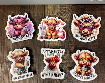 May include: Set of 7 Highland Cow stickers with various sayings. The stickers feature a cartoon Highland Cow with pink sunglasses and a coffee cup. The sayings include "Moody AF", "One Boujee Heifer", "Not Today Heifer", "Apparently I Have An Attitude Who Knew?", and "Coffee Addict".