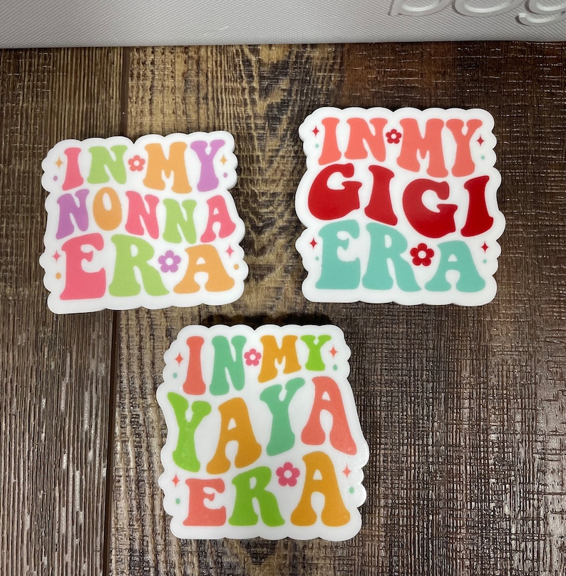 May include: Three white stickers with colorful text that reads "In My Nonna Era", "In My Gigi Era", and "In My Yaya Era".