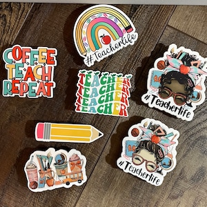 May include: A set of colorful teacher-themed stickers. The stickers feature a rainbow, a pencil, a coffee cup, a teacher with glasses, and the text "Coffee Teach Repeat" and "#Teacherlife".