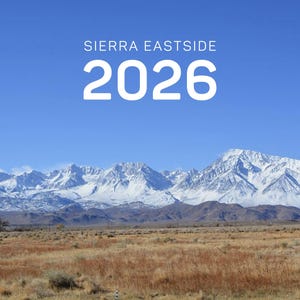 May include: A scenic landscape featuring snow-capped mountains under a clear blue sky. The text "SIERRA EASTSIDE 2026" is displayed in white at the top, above the mountain range and a field of dry grass.