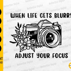 May include: Black and white graphic featuring a camera with floral accents. Text reads "When life gets blurry, adjust your focus." Includes file type icons for SVG, DXF, PNG, EPS, and AI, with "Instant Download" text.