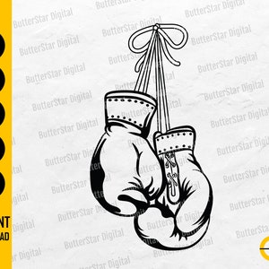 May include: Black and white illustration of boxing gloves hanging by a ribbon. The image includes the text "SVG, DXF, PNG, EPS, AI" and "INSTANT DOWNLOAD". The gloves are detailed with laces and stitching.