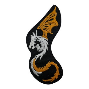 Peut inclure: Un écusson thermocollant brodé représentant un dragon blanc avec des ailes dorées sur fond noir.