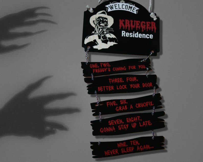 May include: A black wooden sign with a red and white image of Freddy Krueger, the character from the Nightmare on Elm Street horror films. The sign reads "Welcome Krueger Residence" and has a series of smaller signs hanging below with the text "One, two, Freddy's coming for you... Three, four, better lock your door... Five, six, grab a crucifix... Seven, eight, gonna stay up late... Nine, ten, never sleep again..."