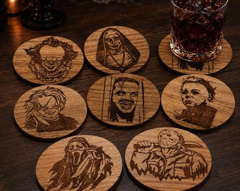 May include: A set of seven circular wooden coasters, each featuring a laser-engraved portrait of a horror movie character. The designs include a clown, a nun, a man peering through a door, a doll, a masked figure, a ghost-faced figure, and a hockey-masked killer.