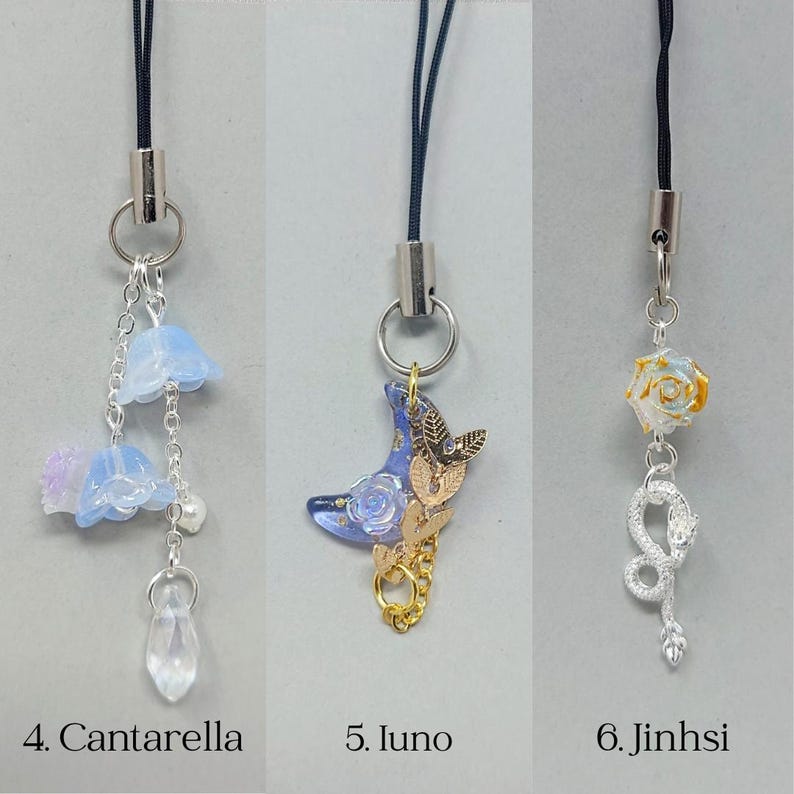 K&ouml;nnte beinhalten: Drei dekorative Handy-Anh&auml;nger. Der erste hat blaue Blumen-Anh&auml;nger und einen Kristallanh&auml;nger. Der zweite hat einen blauen Halbmond mit goldenen Akzenten. Der dritte hat eine Rose und einen Schlangen-Anh&auml;nger. Jeder Anh&auml;nger hat eine schwarze Kordel und silberfarbene Hardware. Der Text auf dem Bild lautet: 4. Cantarella, 5. Iuno, 6. Jinhsi.