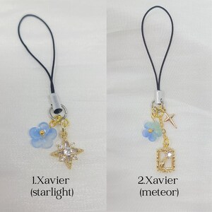May include: Two phone charms with black loops and silver connectors. The first, 1.Xavier (starlight), features a blue flower and a gold star charm with clear crystals. The second, 2.Xavier (meteor), has a blue flower, a small gold cross, and a gold rectangular frame charm with a crystal.