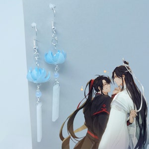 May include: A pair of dangle earrings with a blue flower charm and a white rectangular charm. The earrings are silver and have a hook closure.