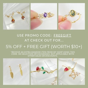 May include: A collage of gold-toned jewelry, including earrings with amber-colored teardrop pendants, rings with purple and green gemstones, a bracelet with a red rose, and a necklace with a heart and bow and arrow charm. Text reads: USE PROMO CODE: FREEGIFT.
