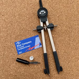 May include: A 6-inch Alvin bow compass with silver metal legs and black plastic accents. The tool includes a central adjustment wheel, a black handle, and a blue product label reading Alvin Bow Compass 6" Pencil Compass/Divider 201.