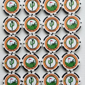 May include: A collection of twenty round poker chips arranged in a grid. Each chip features a white center with a green golf course graphic, a cactus, a palm tree, and a red flag. The text reads Trevor's Bachelor Par-Tee and Scottsdale Arizona.
