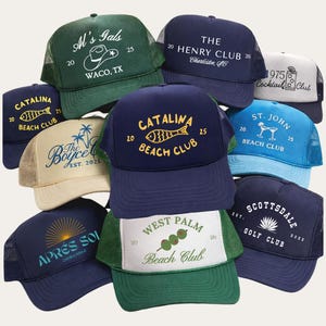 Puede incluir: Una colección de gorras de camionero en varios colores, con logotipos y texto bordados. Los diseños incluyen "Al's Gals", "Catalina Beach Club", "The Henry Club" y "Scottsdale Golf Club". Las gorras tienen la parte trasera de malla y viseras curvadas.