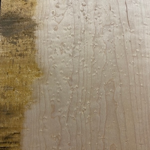 May include: A close-up of a light brown wood veneer with a distinctive burl pattern. The wood has a natural, unfinished look.