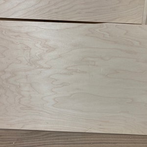 May include: A close-up of a light wood panel with a natural grain pattern. The wood has a smooth, even texture and a light, warm color.